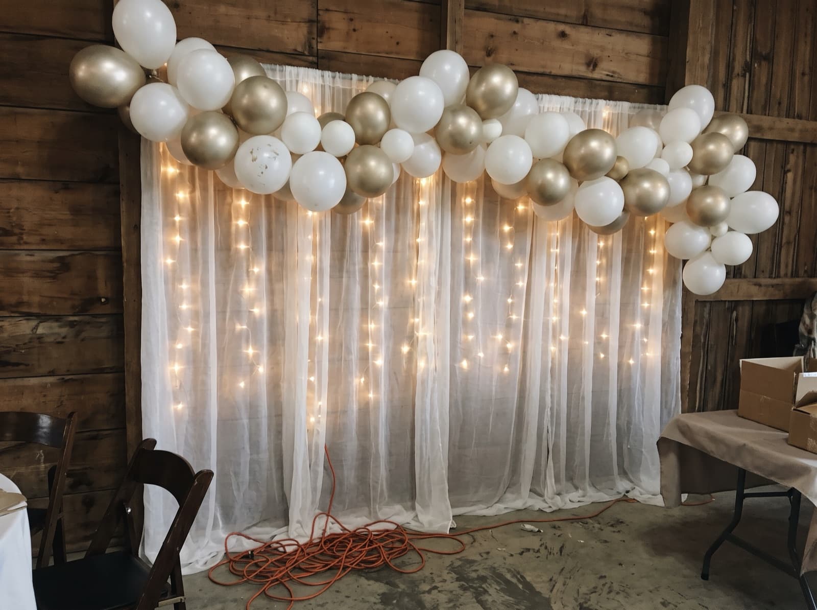 Draped backdrop with balloons and lights in a barn venue