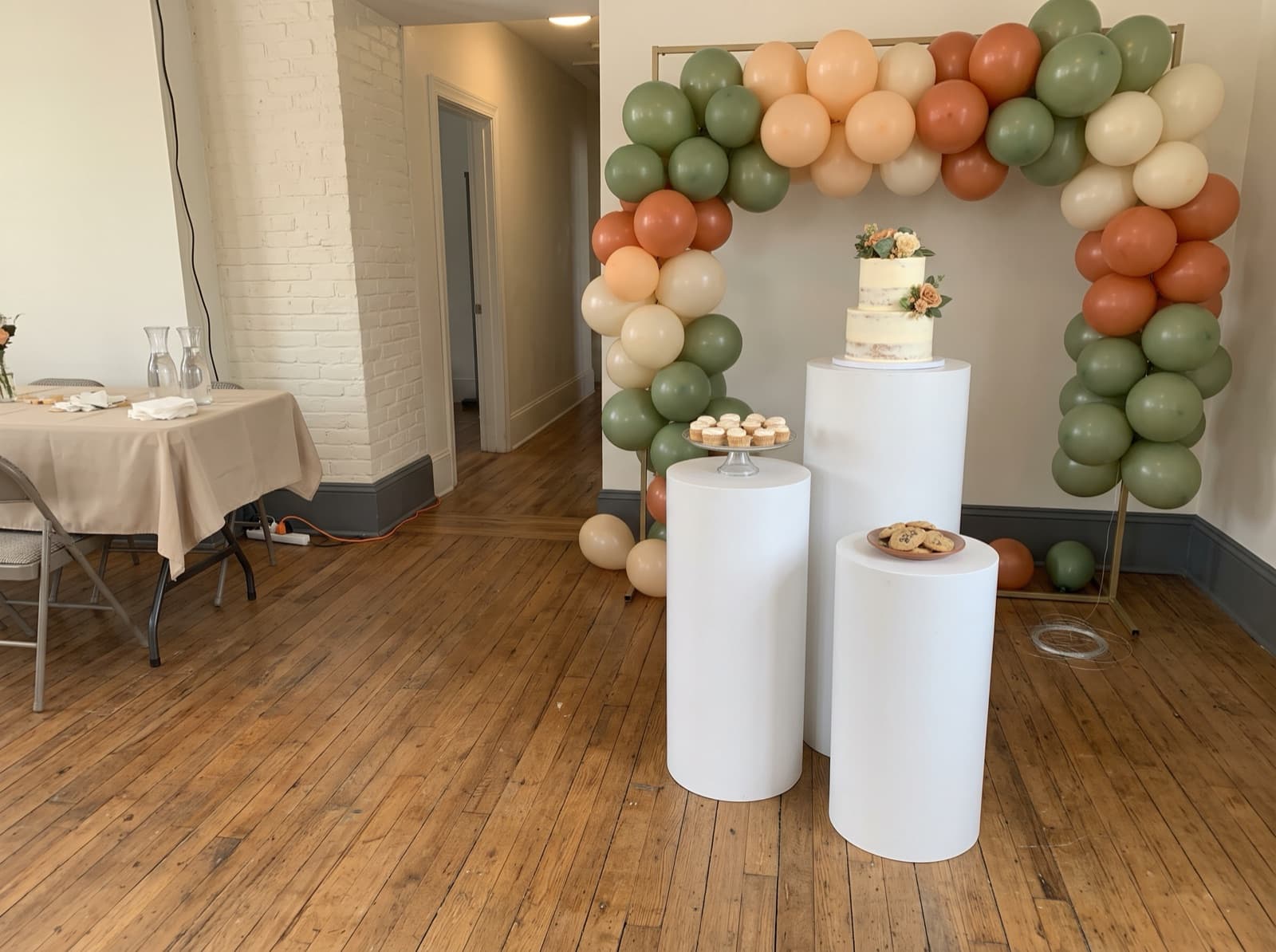 Balloon backdrop with pedestals and a cake table