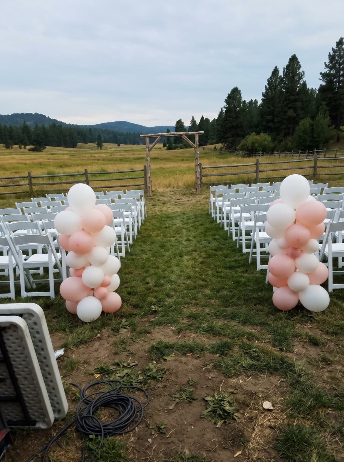 Organic balloon columns lining an outdoor ceremony aisle at a ranch venue