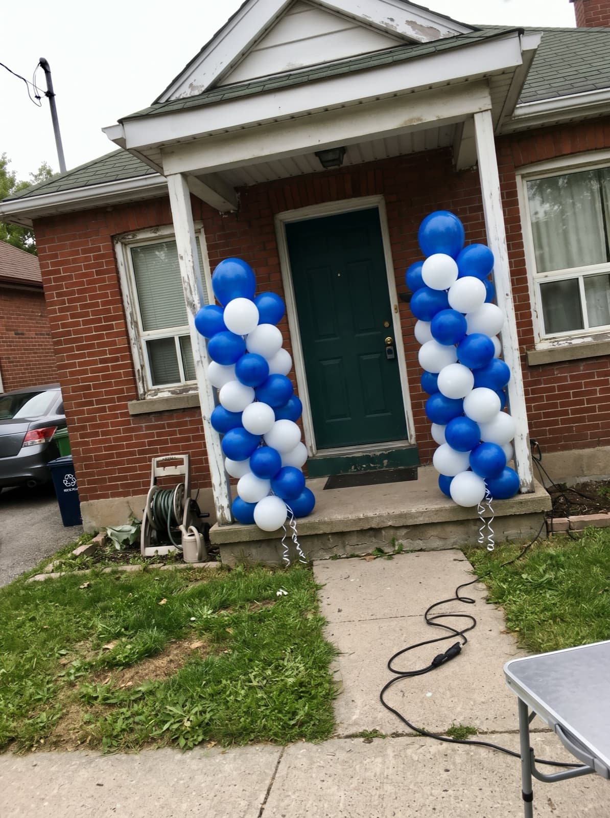 Pair of spiral balloon columns at the front door of a brick bungalow