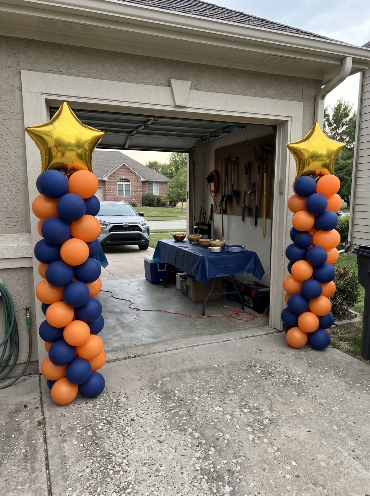 Pair of spiral balloon columns in navy and orange with gold star toppers at a graduation party