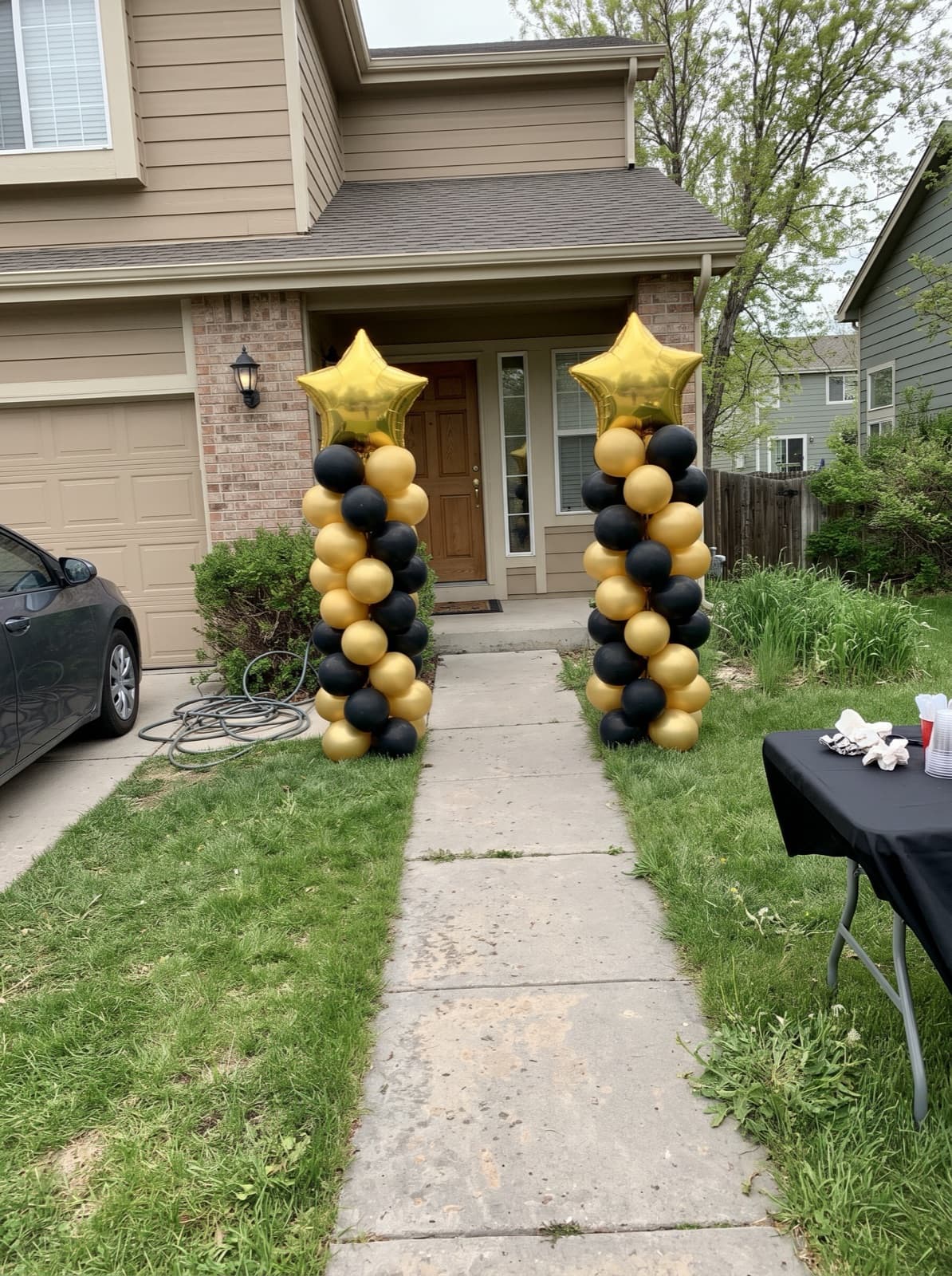 Black and gold balloon columns with star toppers at a front walk
