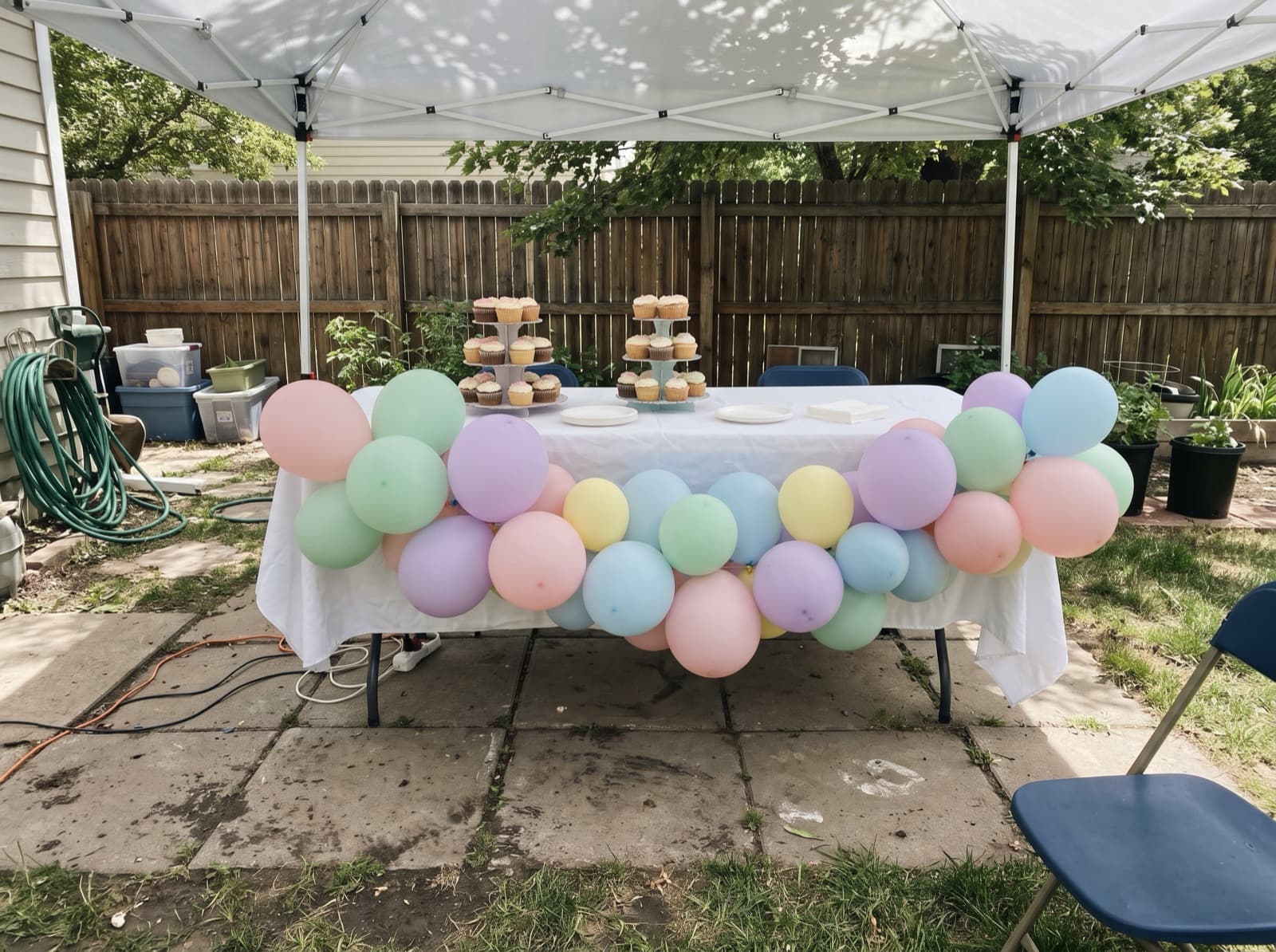 Pastel rainbow balloon garland across a cake table under a canopy