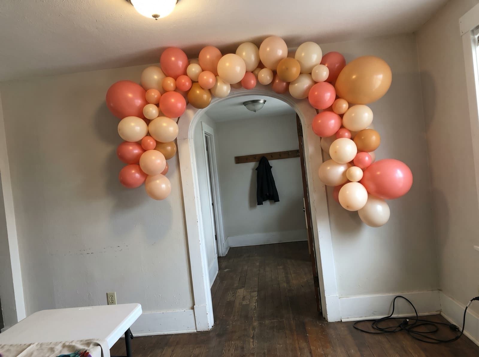 Coral and cream balloon garland around a rounded doorway