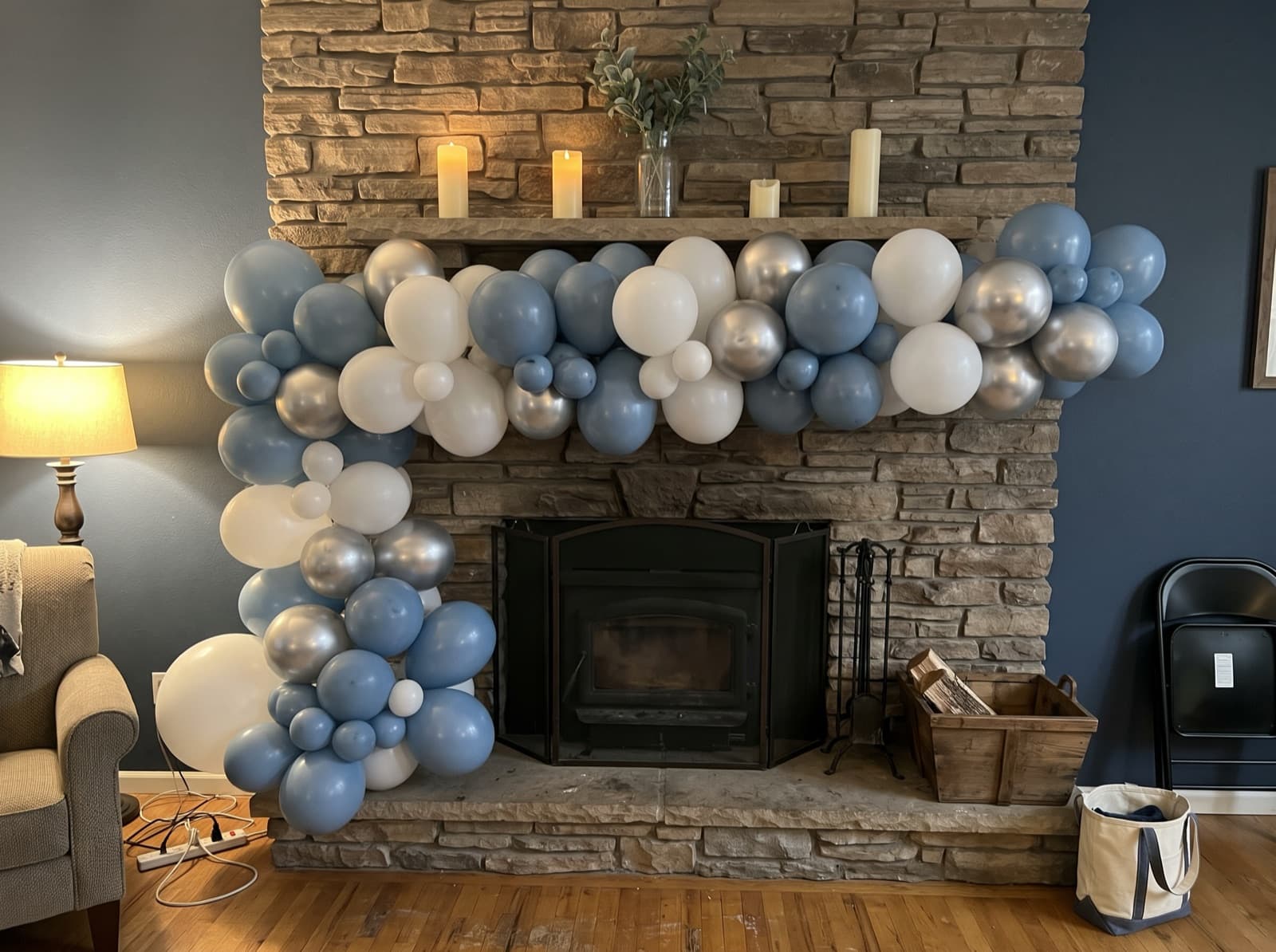 Organic balloon garland in dusty blue, white and silver along a stone fireplace mantel in a Denver home