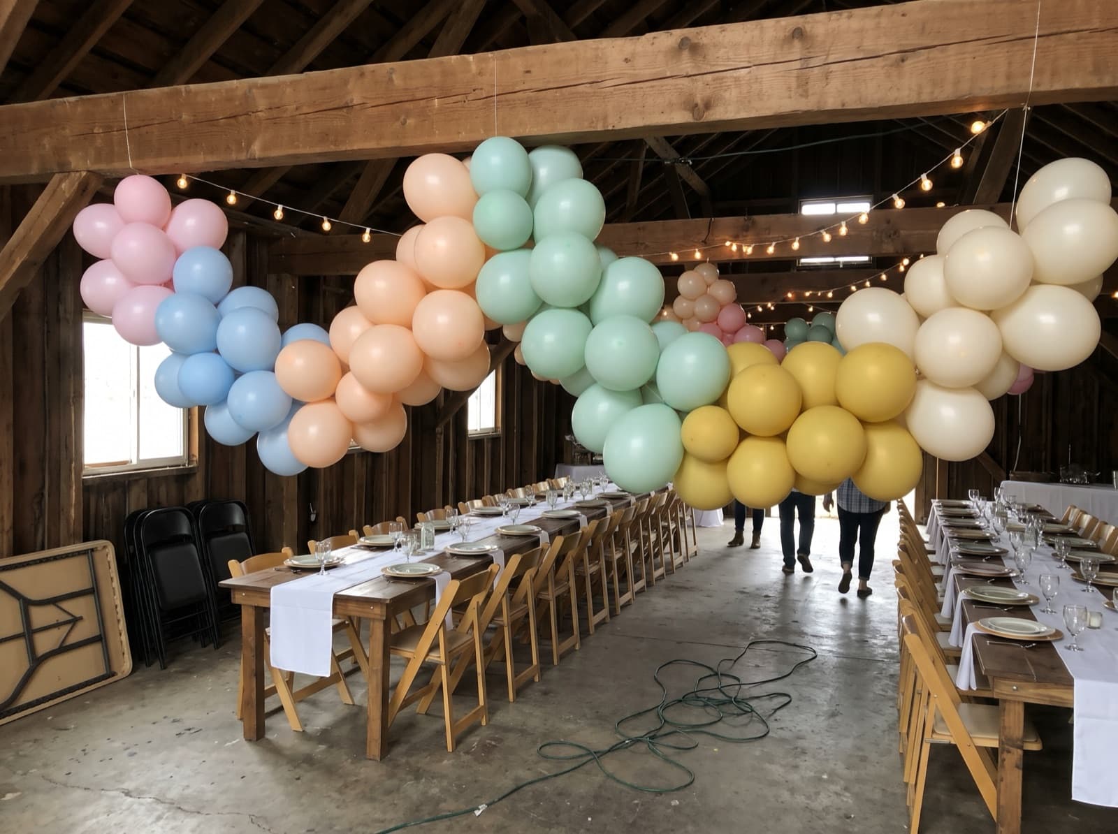 Hanging balloon garland canopy over dining tables in a barn