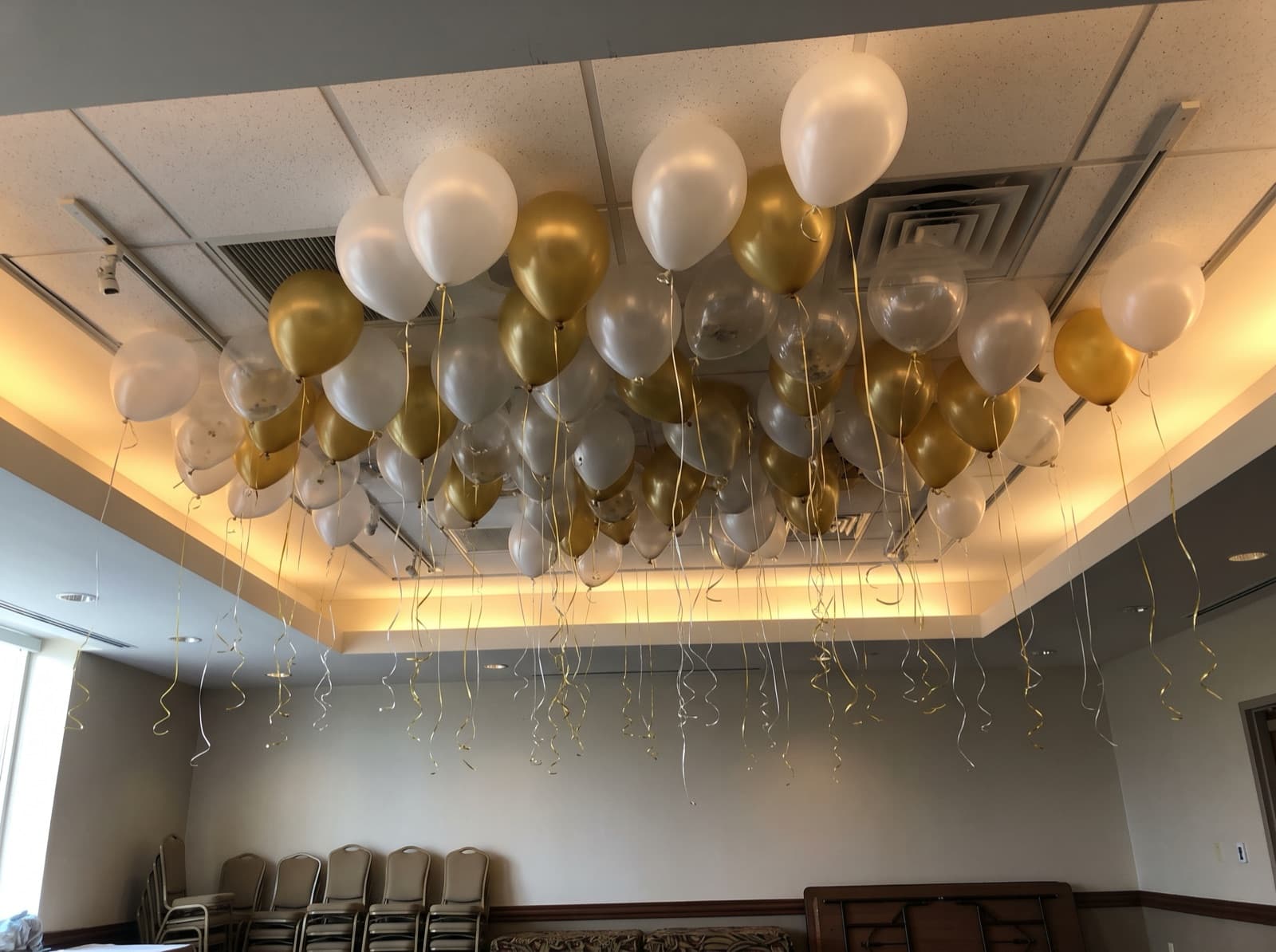 Balloon ceiling of white, clear and gold balloons over a ballroom dance floor