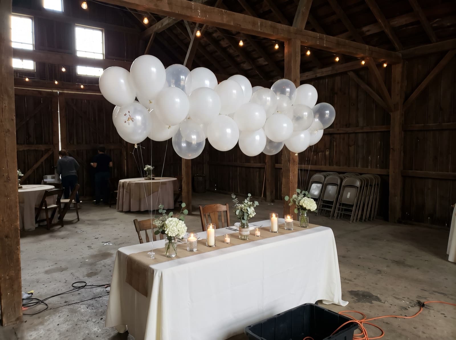 Balloon cloud over a sweetheart table in a barn reception