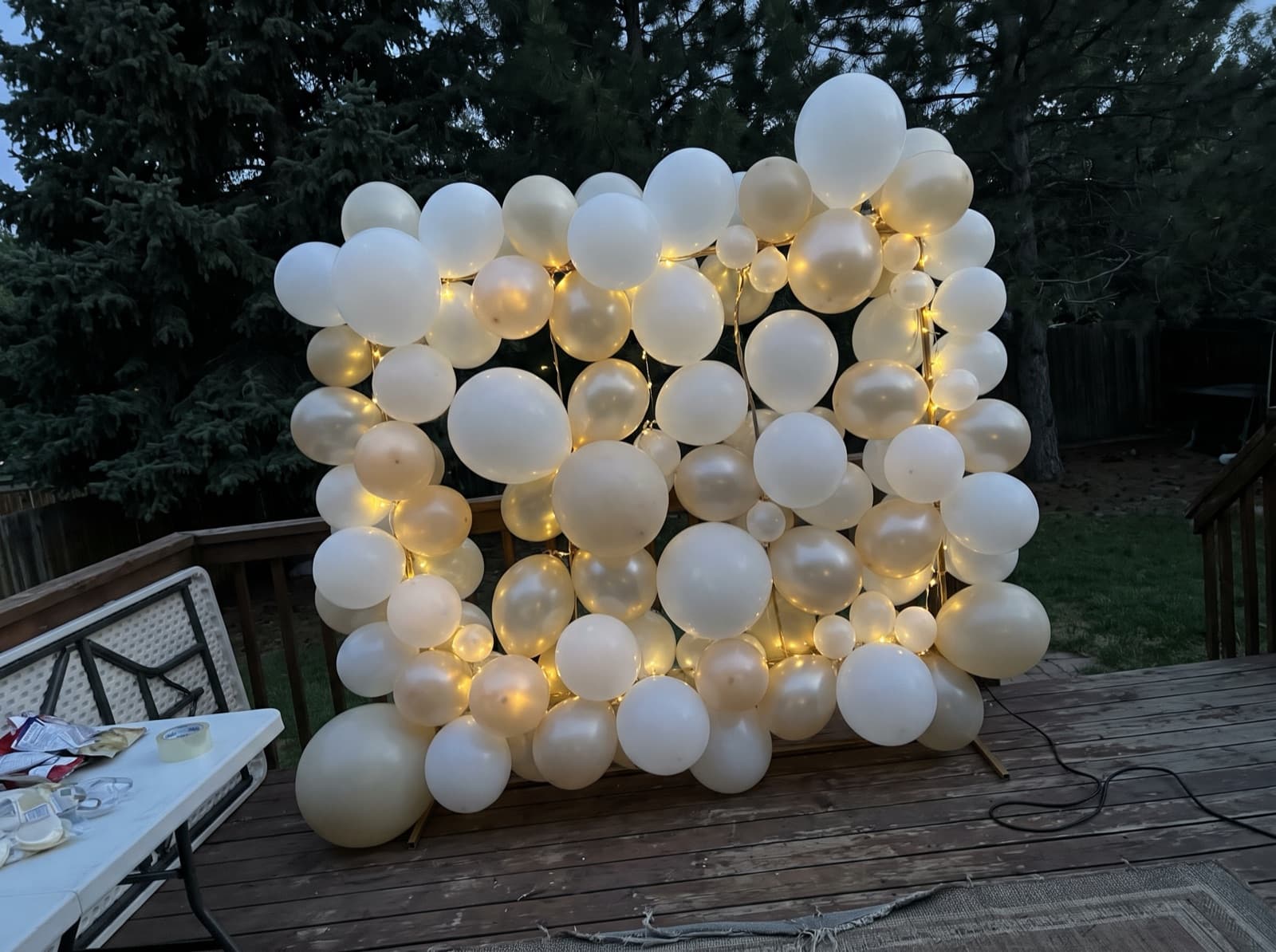 Balloon wall with string lights on a covered deck at dusk